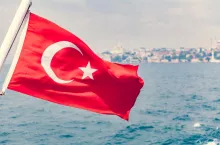 Turkey flag waving over blue sky and sea background
