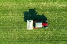 Agricultural tractor is fertilizing wheat crop field with NPK fertilizers, aerial view from drone pov