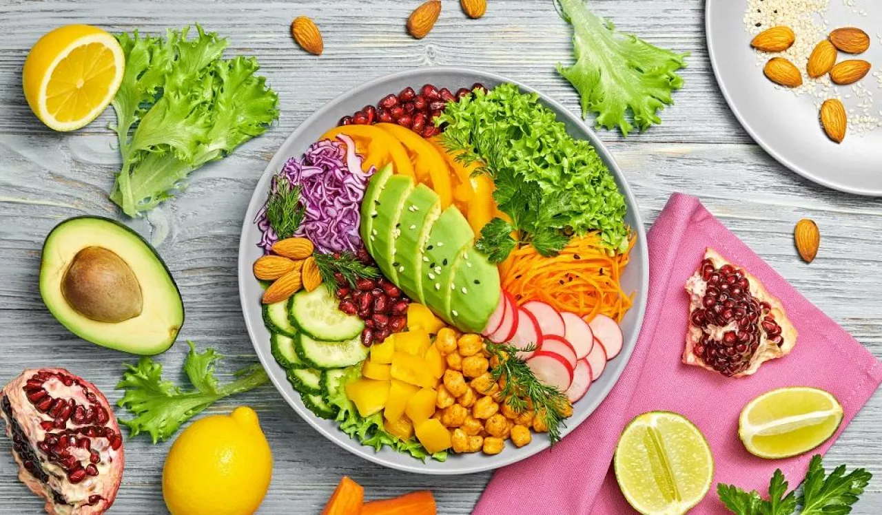Buddha bowl salad with avocado, tomato, lettuce, cucumber, red cabbage, chickpeas, pomegranate. Paleo diet, healthy vegan and balanced food concept. Fresh rainbow mix green salad on wood
