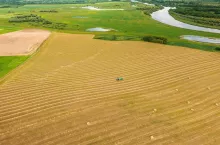 Aerial View Tractor Collects Dry Grass In Straw Bales In Wheat Field. Special Agricultural Equipment. Hay Bales, Hay Making. Farmland