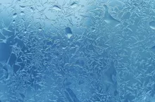 Natural ice pattern and water drops on winter window glass