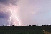 Lightning bolt at night over rural area. Agriculture fields.