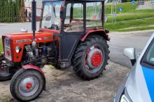 Ciągnik rolniczy stojący obok policyjnego radiowozu