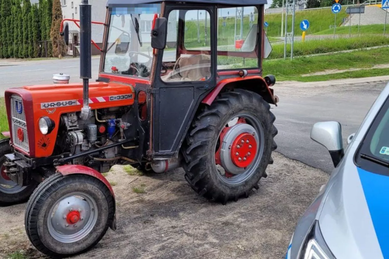 Ciągnik rolniczy stojący obok policyjnego radiowozu