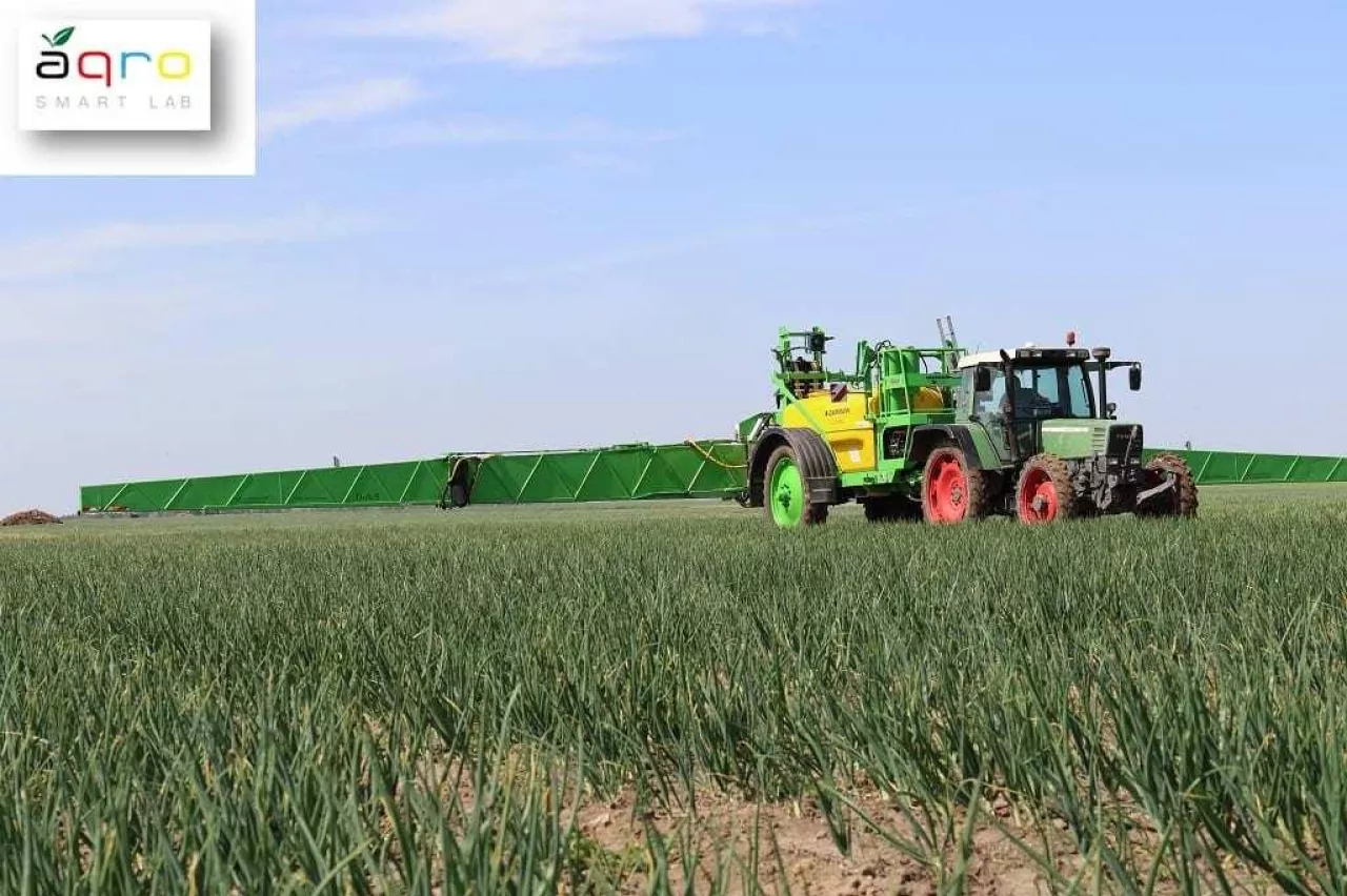 ciagnik z opryskiwacze na polu cebulu