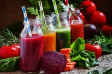 Freshly squeezed vegetable juice in bottles, useful vitamin cocktail, old wooden background, selective focus