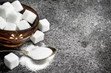 Sugar in a teaspoon. On a rustic background.