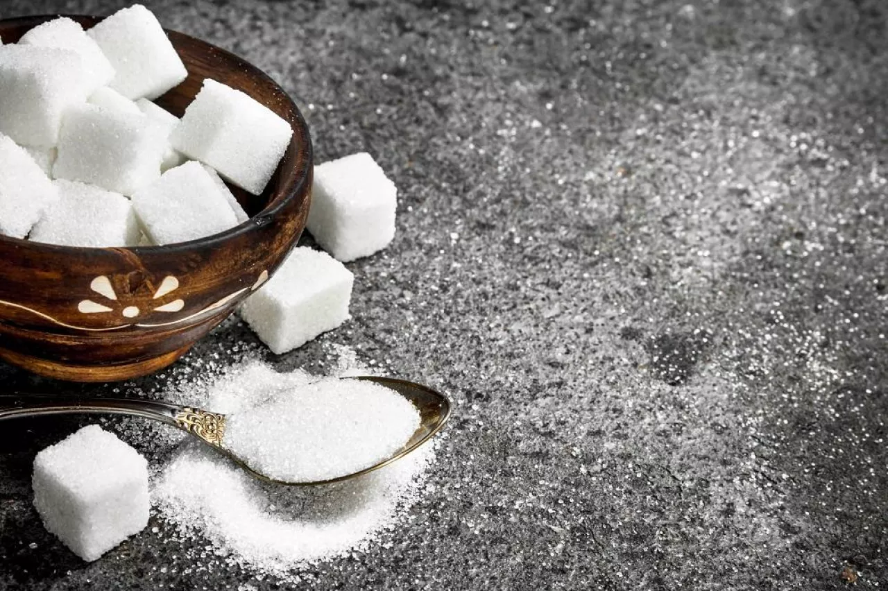 Sugar in a teaspoon. On a rustic background.