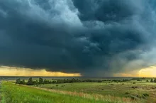 Panorama of a massive mesocyclone weather supercell, which is a pre-tornado stage, passes over a grassy part of the Great Plains while fiercely trying to form a tornado.