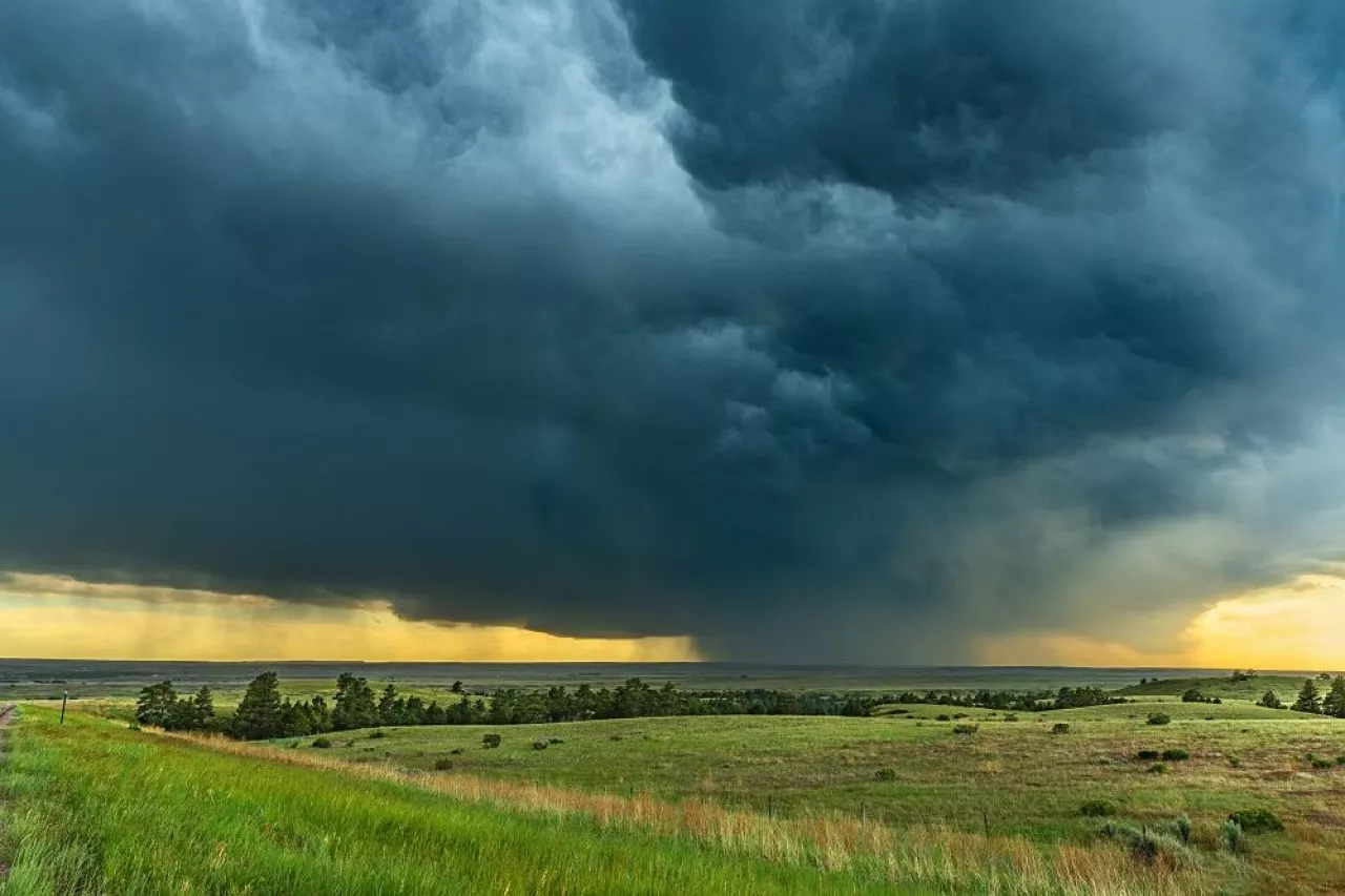 Panorama of a massive mesocyclone weather supercell, which is a pre-tornado stage, passes over a grassy part of the Great Plains while fiercely trying to form a tornado.