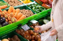 The hands of a senior woman choose onions at the supermarket. A counter full of various types of vegetables for a healthy diet