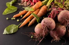 Close-up of carrots and beetroots with green peas and leaf vegetable on black background. unaltered, copy space, vegetable, healthy food, raw food, variation and organic concept.