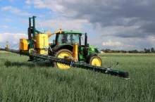 Ciągnik z opryskiwaczem na polu